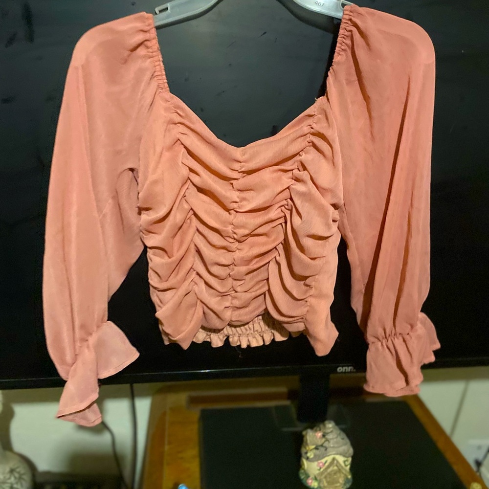 A cropped long sleeve ruffled blouse with a cool pink tone